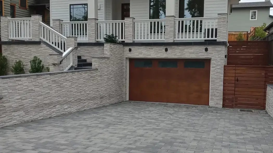 Finished home exterior with railings, stone veneer and a paver driveway