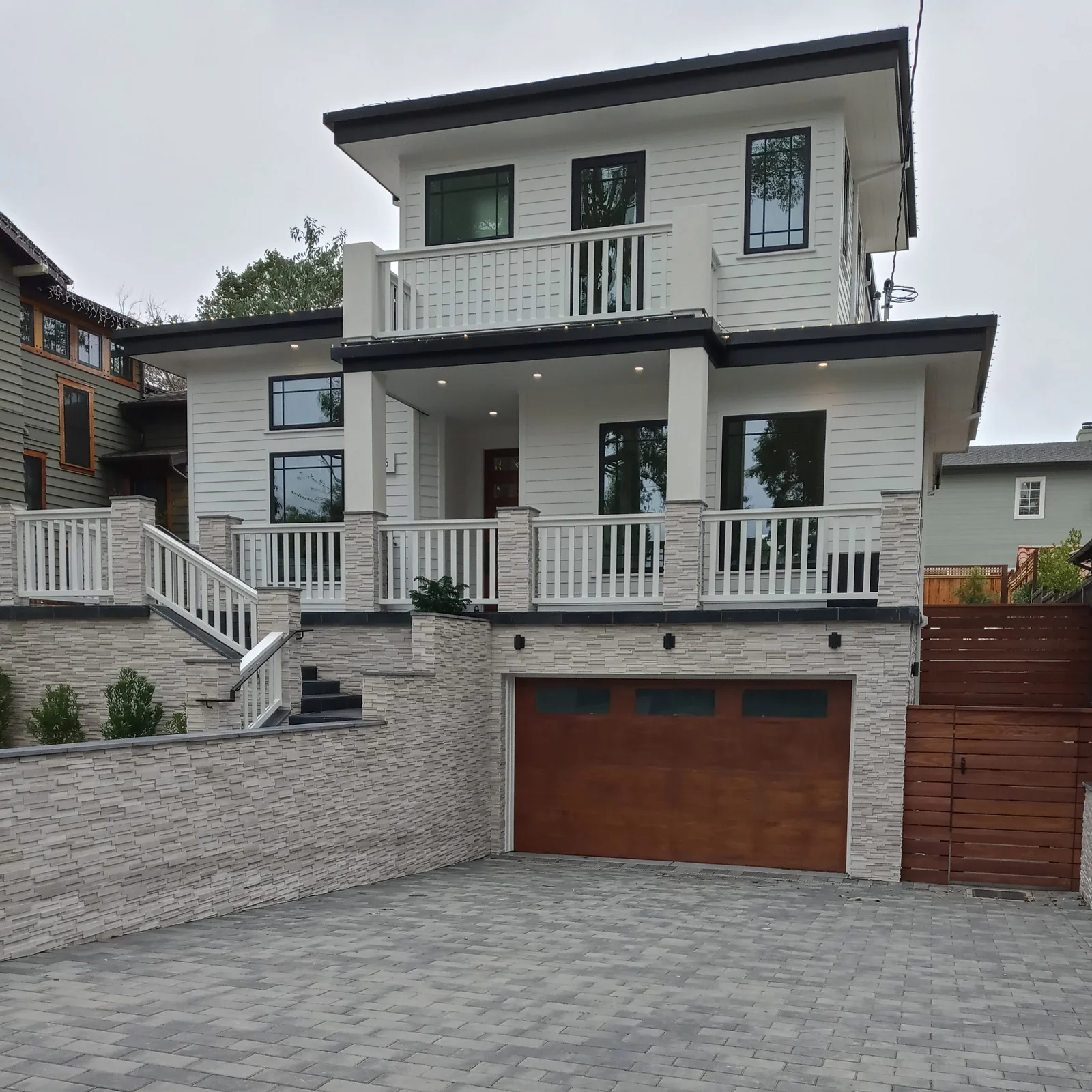 Fachada remodelada con porche, revestimiento de piedra y entrada adoquinada